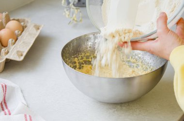 Metal bir kasede yumurta, un, süt, tarçın ve kakule karıştırarak organik malzemelerden mis kokulu bir sonbahar pastası hazırlıyorum. Ev yapımı pişirme için mükemmel..