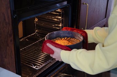 Tarçınlı güzel kokulu bir elmalı turta fırından çıkarılıyor. Baharat şeklinde bir tavada kırmızı eldivenler var. Ev yapımı mevsimlik pişirme için mükemmel..