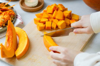 Kadınların ellerini kapayın. Tahta kesme tahtasıyla taze balkabağını küp yapın. Kavrulmuş balkabağı, çorba, turta, güveç ya da sonbahar yemekleri hazırlayın..