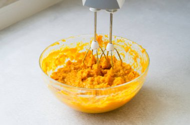 Balkabağı püresi cam kaseyle karıştırılıyor. Kabak turtası ya da peynirli kek hazırlıyorum. Sonbahar aşçılığı ve tatlı tarifleri aşaması.