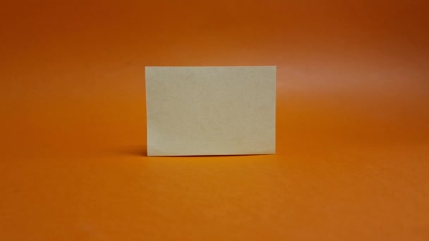 オレンジ色の背景に白い紙を引く男の手 事業概念 — ストック動画