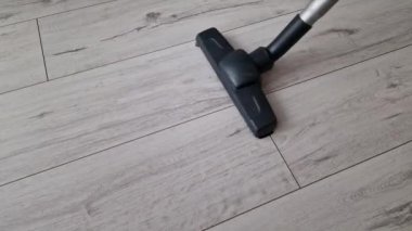 Modern elektrikli süpürgeyle ahşap zemini süpürüyor. Oda servisi, ev işleri, hijyen kavramı.
