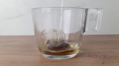 Kırsal ahşap masada çay içerken fincana sıcak su dökmek. Çay demleme konsepti. Yavaş çekim