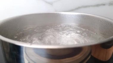 Mutfaktaki ocağın üstünde kaynar su olan tencere. Yavaş çekim