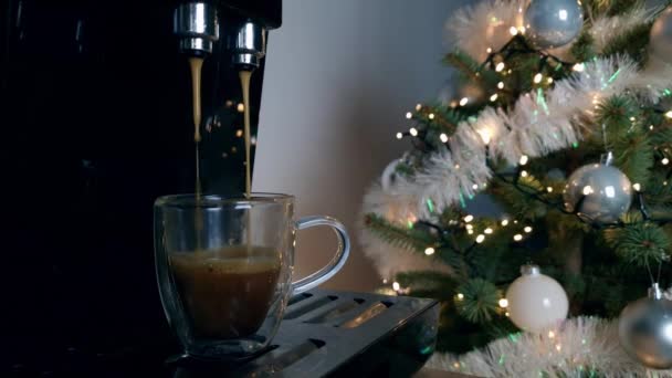 コーヒーマシンは小さなエスプレッソを作る 背景にライトや装飾が施されたクリスマスツリー 新年の休憩の概念 スローモーション — ストック動画