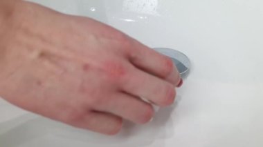 Bir kadının eli suyu doldurmak için tıpayı tıkar. modern lavabo, su tasarrufu kavramı