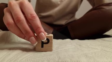 Woman composes the word PMS from wooden blocks. Premenstrual syndrome concept