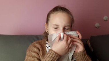 Little child girl blows her nose. Sick child with napkin at home. Allergic kid, flu season concept