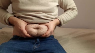 Obese man holding his belly. Abdominal obesity is a cause of diabetes and high blood pressure