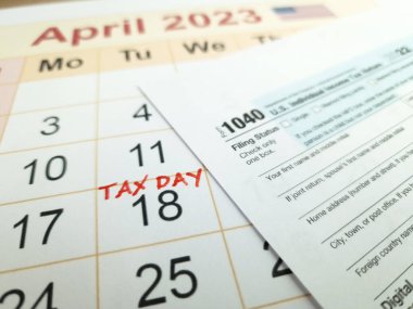 Tax payment day marked on a calendar - April 18, 2023 with 1040 form, financial concept