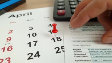 Tax payment day marked on a calendar - April 18, 2023 with 1040 form, financial concept