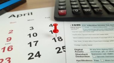 Tax payment day marked on a calendar - April 18, 2023 with 1040 form, financial concept