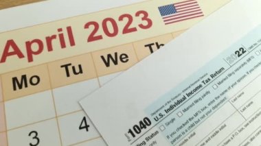 Tax payment day marked on a calendar - April 18, 2023 with 1040 form, financial concept