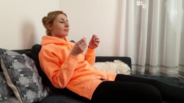 Mulher Caucasiana Atraente Colocando Fones Ouvido Enquanto Sentado Sofá Casa — Vídeo de Stock