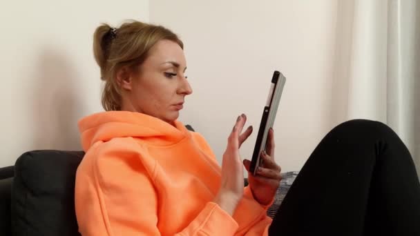 Mulher Caucasiana Jovem Escrevendo Dados Computador Tablet Enquanto Sentado Sofá — Vídeo de Stock