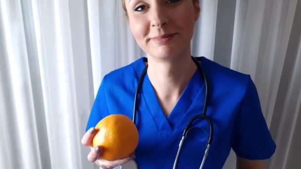 Happy Young Caucasian Healthcare Professional Promoting Healthy Eating Holding Orange — Stockvideo