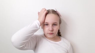 Serious little girl scratching her head. Uncertain with doubt, thinking, planning, overcome problem concepts. White wall background