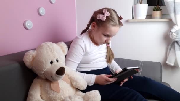 Маленькая Девочка Сидящая Диване Используя Цифровой Планшет Сидя Одна Дома — стоковое видео