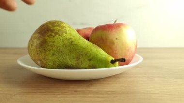 Elle olgun yeşil armudu tabaktan alır. Sağlıklı atıştırmalıklar, organik beslenme, taze gıda kavramları.