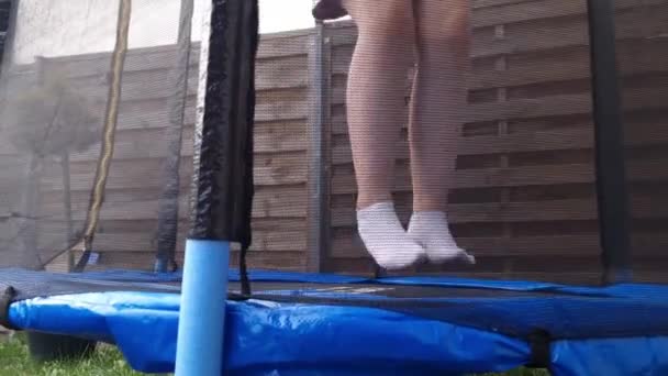 女の子は家の庭にトランポリンでジャンプします レジャーアウトドアアクティビティ 子供時代のコンセプト — ストック動画