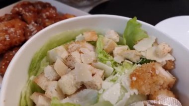 Kızarmış tavuklu salata, marul, kızarmış ekmek ve acı sos.
