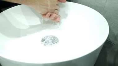 Evde banyo lavabosunda sabun ve sıcak suyla ellerini yıkamak, hijyen kavramı.