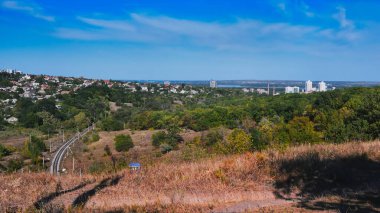 Scenic panorama of Tonelna Balka in Dnipro, Ukraine, photographed on September 16, 2025. Railway tracks, green forest and modern city skyline create a mix of nature and urban landscape.
