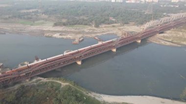 Aerial Drone shot of a Indian railways train crossing a bridge next to Red Fort Yamuna River in New Delhi India 