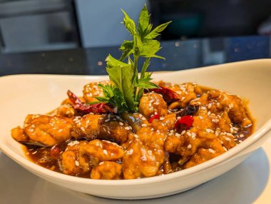 spicy fried chicken garnished with fresh herbs and chili peppers in a white serving dish. Perfect for Asian cuisine, restaurant menus, and street food concepts.