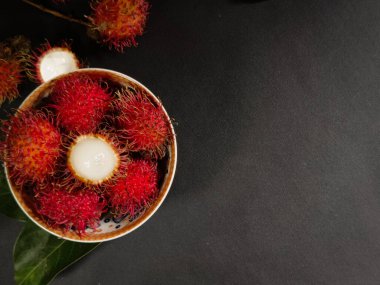 tatlı ve taze tropikal meyveli rambutan siyah bir zemin üzerinde otururken fotokopi alanı ile