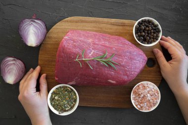 Siyah mermer kaplı arka planda çiğ kırmızı et, üst manzara. Kesme tahtası kadın eli.. 