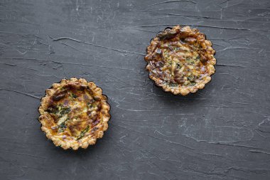 Quiche with asparagus and cheese on black marble background, top view. 