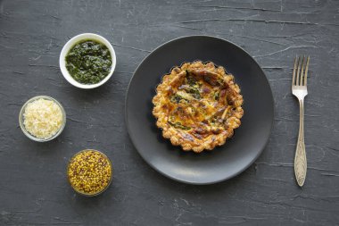 Tasty asparagus tart with cheese and spices on black background, top view. 