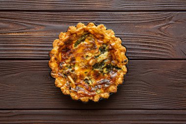 Tasty vegetable tart with cheese, quiche lorraine on wooden rustic table, top view. 