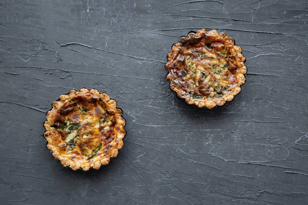 Quiche with asparagus and cheese on black marble background, top view. 