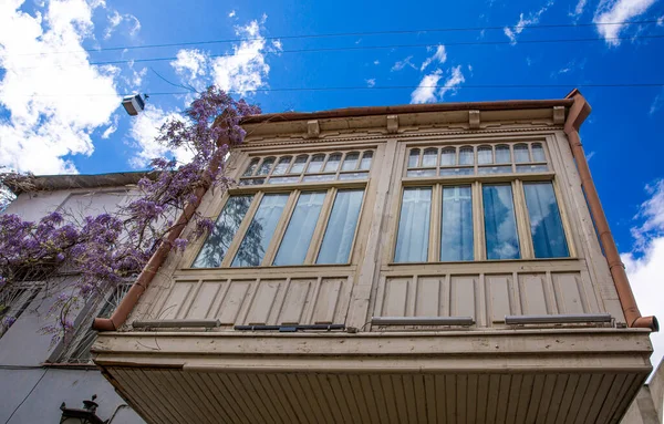 stock image Traditional carved wooden balcony and beautiful wisteria in old Tbilisi, Georgia. Bright blue sky. 