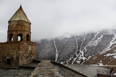 Gergeti 'deki Tsminda Sameba (Kutsal Üçlü veya Cminda Sameba) kilisesi. Kazbegi, Georgia. Sisli, sisli ve kar. 