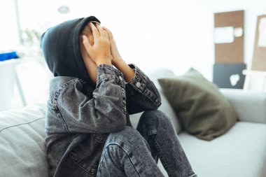 Çocuk istismarı mağduru küçük çocuk kanepeye kıvrıldı. Depresyonda olan 6 yaşındaki bir çocuk ağlıyor. Hafif arkaplan. Çocuk endişeli ve stresli, çocuk evde kalıyor, çocuk sıkılmış ve yorgun.