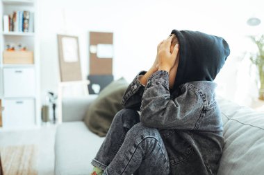 Depresyondaki üzgün çocuk evde, yatakta oturuyor. Küçük çocuk kafasını ellerinin arasında saklıyor. Kafası karışık sorunlu çocuk, çocukluk kabadayılığı, depresyon stresi veya hüsran konsepti