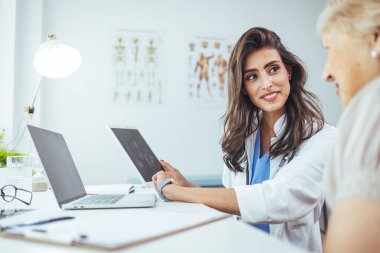 Doktor ve hasta hastanedeki dijital tablete bakıyorlar.