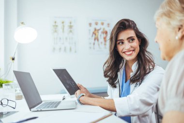 Doktor ve hasta hastanedeki dijital tablete bakıyorlar.