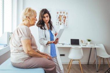 Kadın doktor ve kıdemli hastası tablet bilgisayara bakıyor.