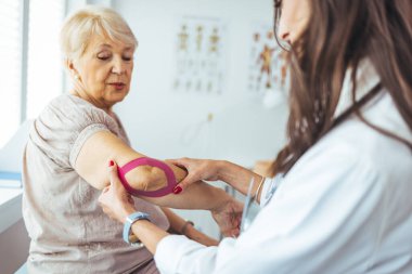  Hasta dirseğine bant yapıştıran fizyoterapist.