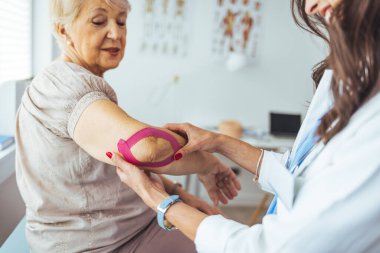  Hasta dirseğine bant yapıştıran fizyoterapist.