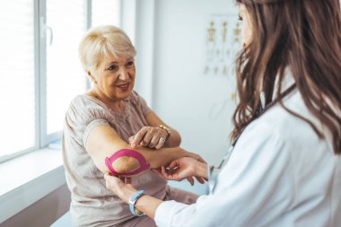  Hasta dirseğine bant yapıştıran fizyoterapist.