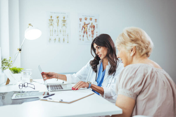 врач и пациентка сидят за столом в больнице и смотрят на ноутбук