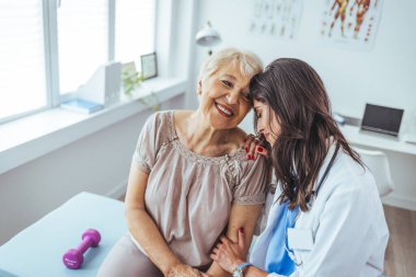 Neşeli ve arkadaş canlısı gülümseyen kadın bir doktor ve klinikteki kıdemli bir hastanın portresi.