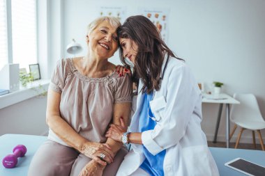 Neşeli ve arkadaş canlısı gülümseyen kadın bir doktor ve klinikteki kıdemli bir hastanın portresi.