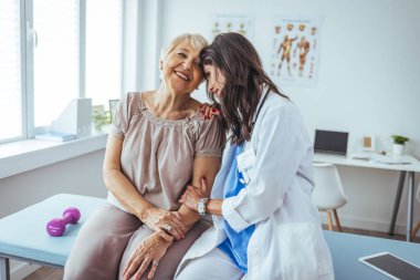 Neşeli ve arkadaş canlısı gülümseyen kadın bir doktor ve klinikteki kıdemli bir hastanın portresi.