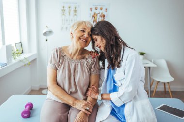 Neşeli ve arkadaş canlısı gülümseyen kadın bir doktor ve klinikteki kıdemli bir hastanın portresi.